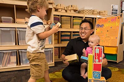child care teacher with toddlers playing with blocks