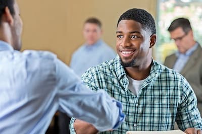 two people sitting and shaking hands