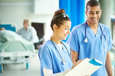 Two nurses looking at clipboard in patient room