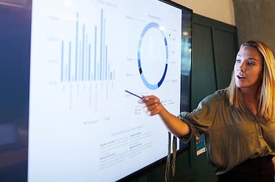 trainer pointing at a smart board with charts