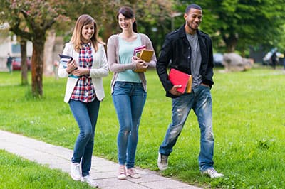 students walking outside holding books