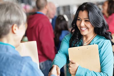 women with clipboards shaking hands