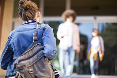 student with backpack walking into building entrance