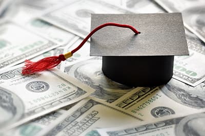 paper graduation cap on top of pile of money