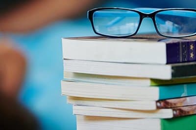 eyeglasses on top of pile of books