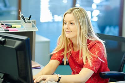 girl sitting at desk typing on computer