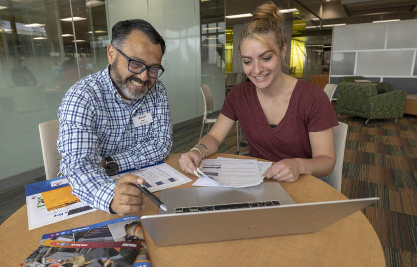 FVTC employee pointing to laptop screen with pen showing a female student something on the screen while both are smiling and happy