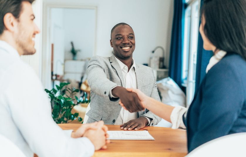 person shaking hands with potential employer across table