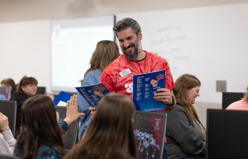 Fox Valley Tech staff member handing out new student orientation folders to students at tables