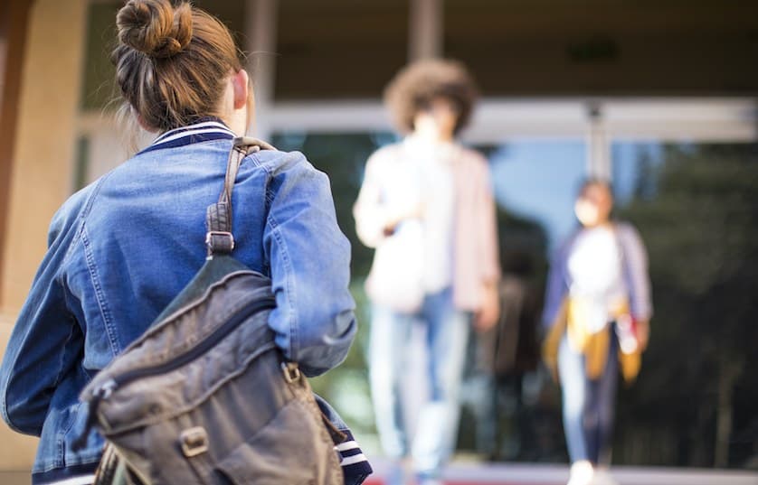 student walking to building with backpack