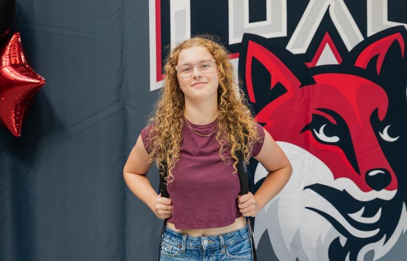 student smiling at camera holding backpack