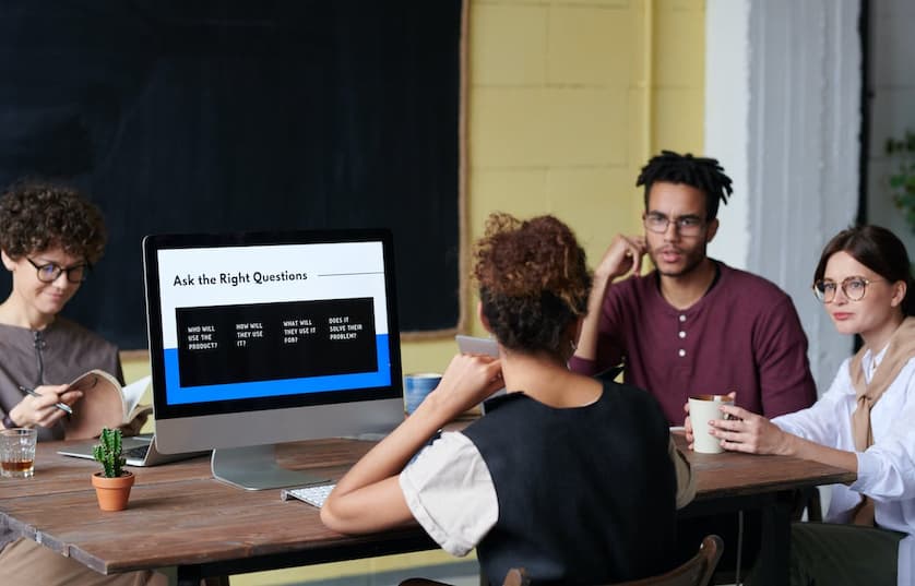 people sitting around table with computer monitor