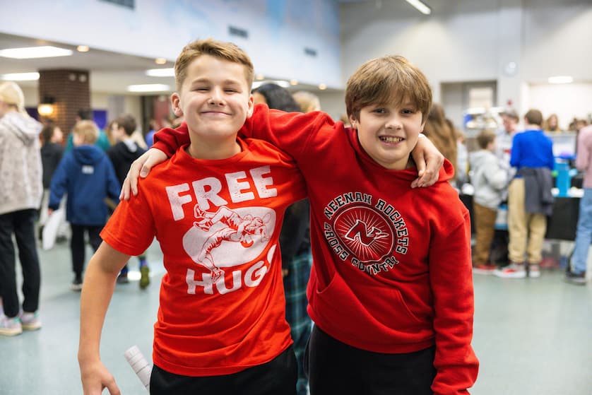 Two summer camp students with arms around each other's shoulders smiling