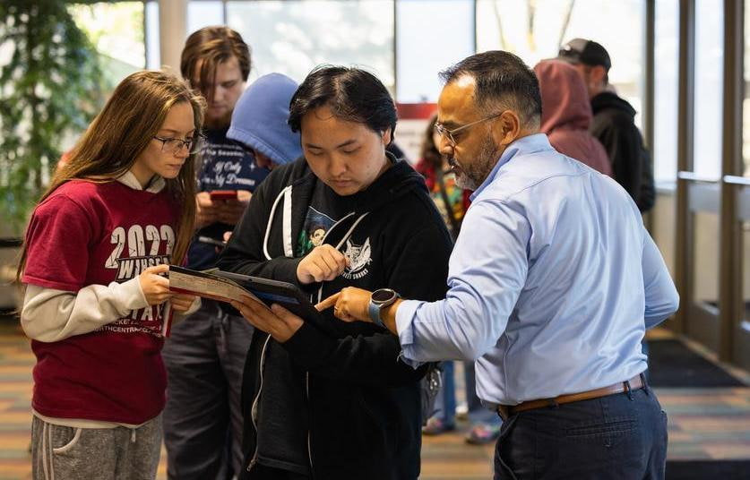Fox Valley Tech staff member helping visitors while pointing to a map held in their hands
