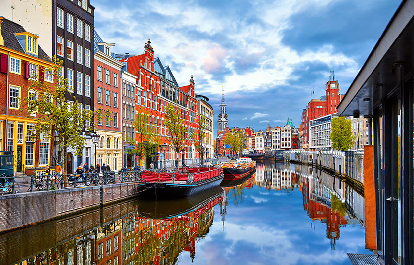 Image of a calm channel of water running between colorful buildings in Amsterdam