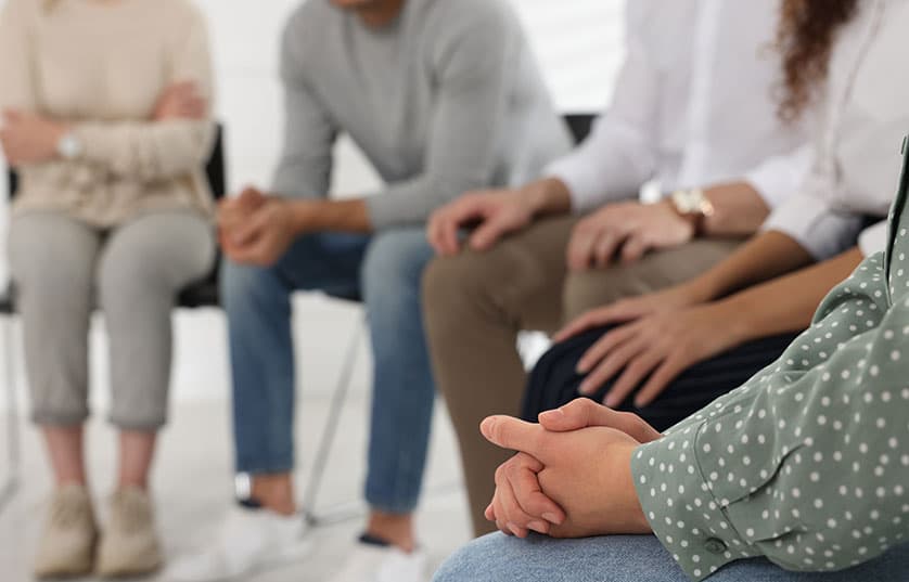 group of people sitting in a room in a circle of chairs