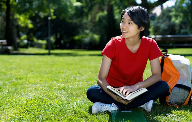 girl sitting on the grass with book