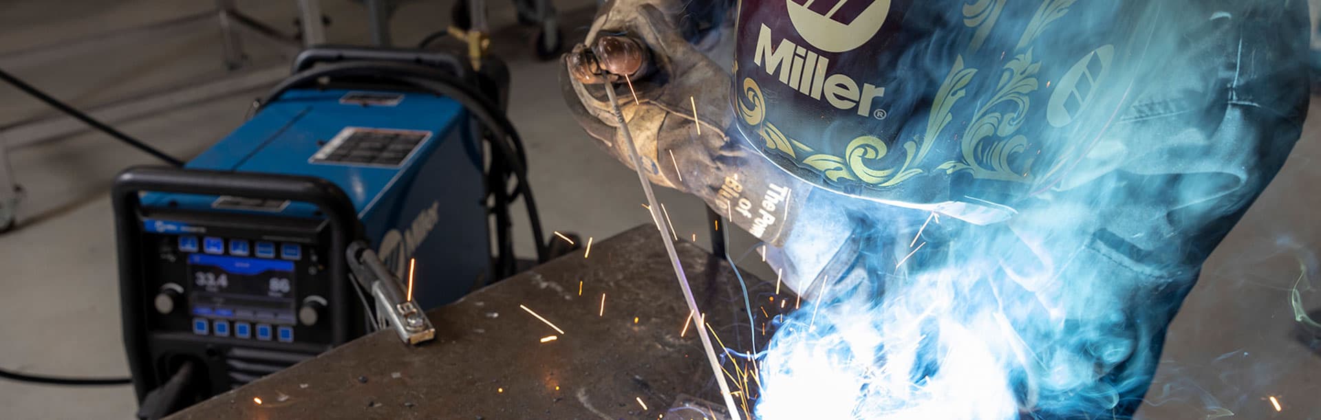 person in welding helmet welding with sparks flying