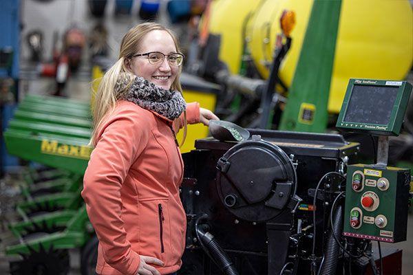 woman standing next to farm equipment in a shop