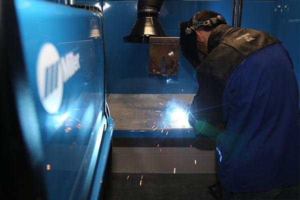 person welding wearing welding jacket and helmet