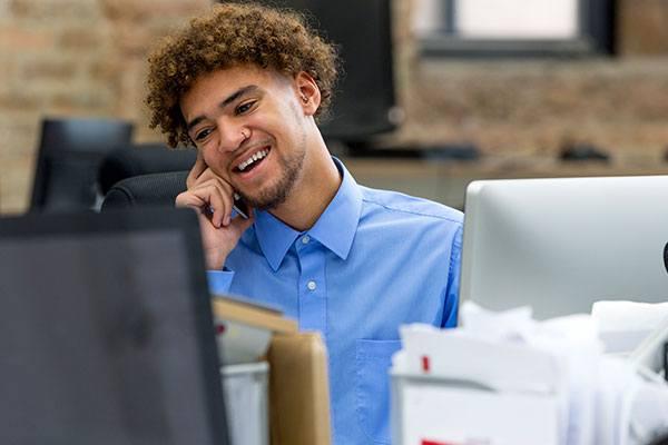 a person sitting at a desk talking on a mobile phone