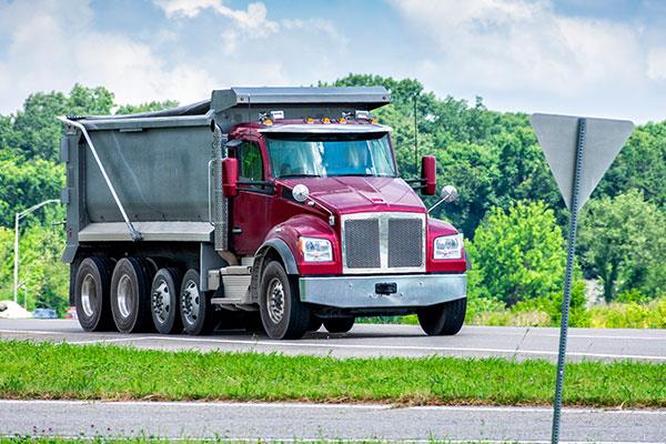 red and silver dump truck driving down the road