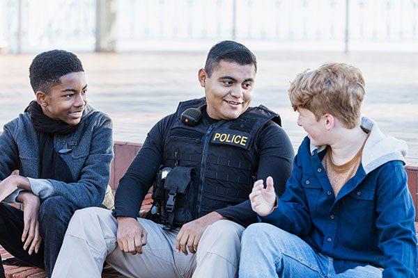 police officer sitting between two boys talking and smiling