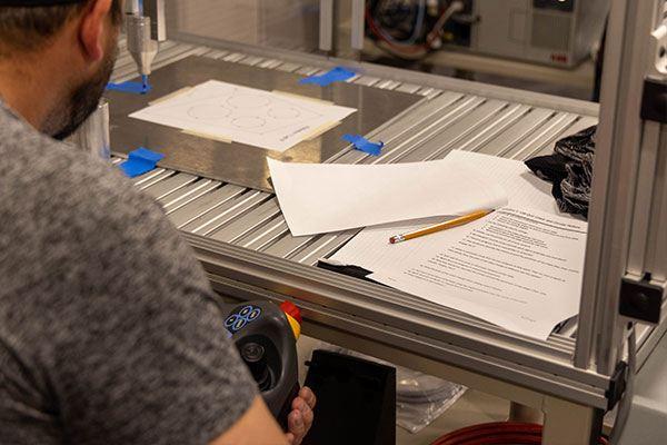 person working on a machine with papers and pencil inside