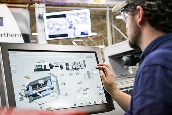 man in cap and safety glasses working on touchscreen computer monitor