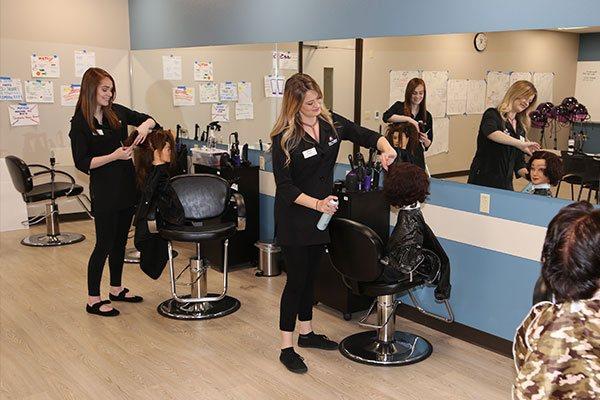 stylists working on hair of cosmetology mannequin head