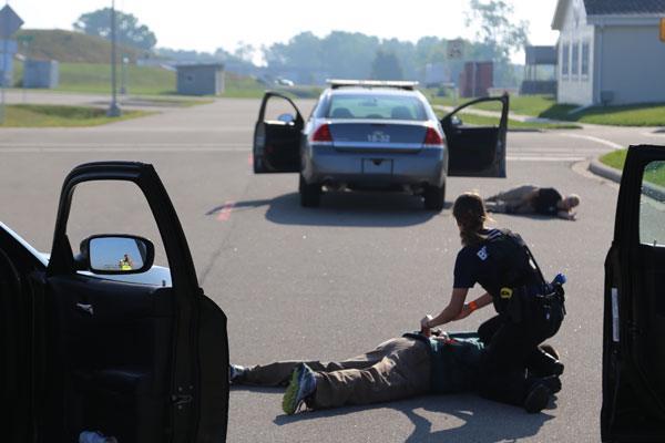 police officer trainee handcuffing person on ground with training police car and FVTC Public Safety Training Center grounds in background