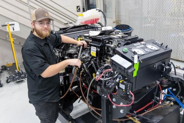 mechanic student working with tool on workbench next to FVTC semi truck