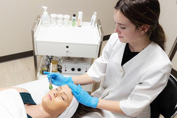 student working on a client's face in aesthetician lab