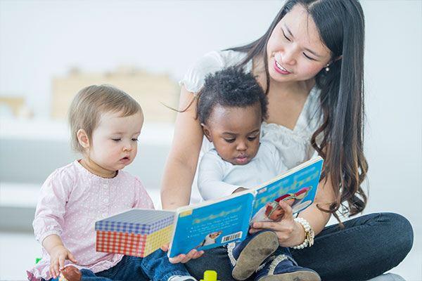 woman reading book to two small children
