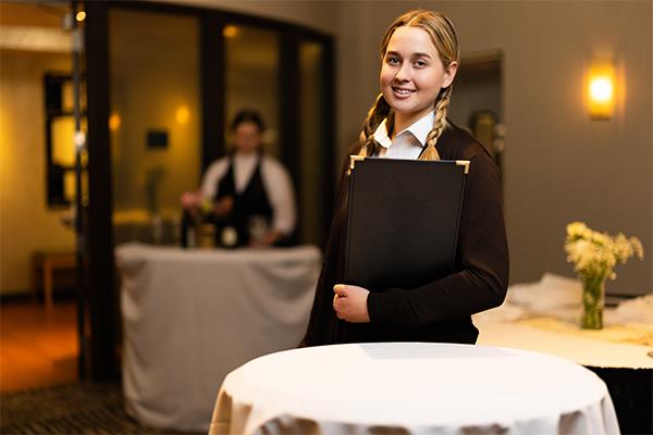 person in shirt and tie learning how to arrange place setting at table