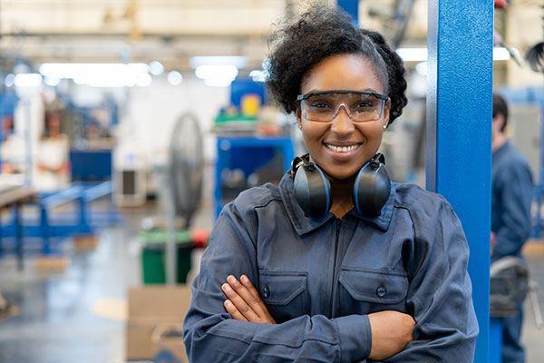 smiling woman crossing arms standing in shop wearing safety glasses and ear protection