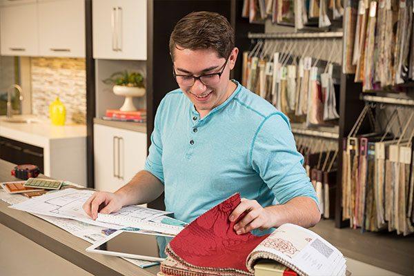 student in interior design classroom flipping through fabric swatch book