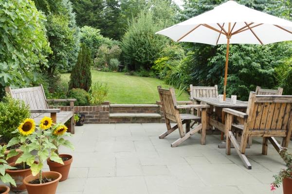 outdoor patio scene with table, bench and greenery