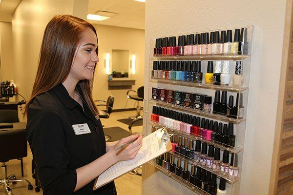 nail tech student with a clipboard looking at nail polish