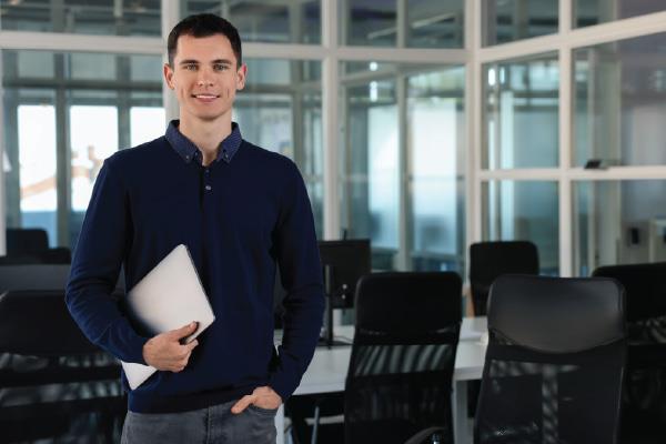 Male holding laptop in conference room