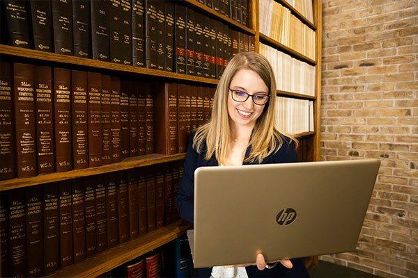 woman in legal library holding open laptop computer