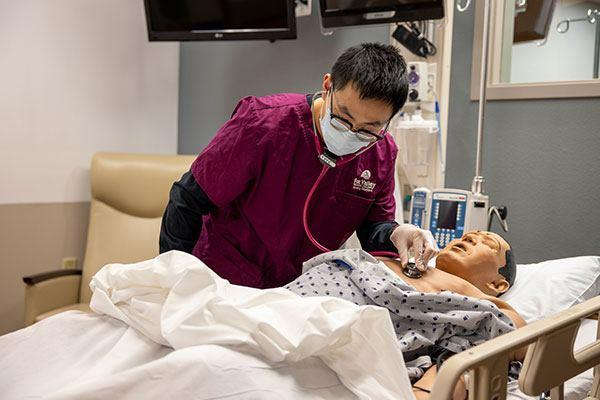 nursing student in lab checking on a patient