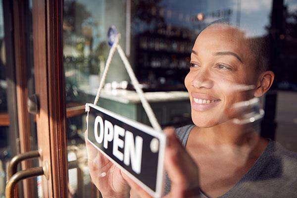 business woman putting open sign on door