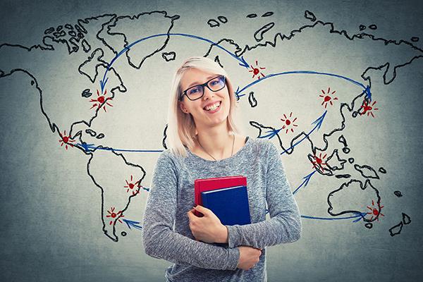 student standing in front of a global map