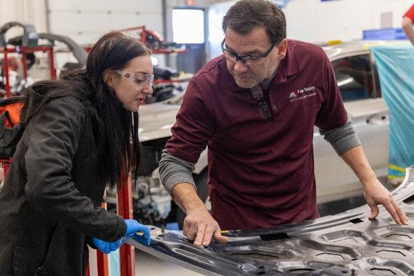 student and instructor working on the hood of a car