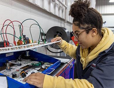 female student working on car electronics