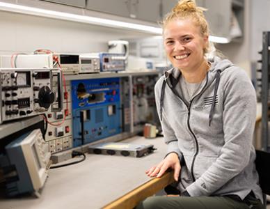 smiling woman sitting next to aircraft electronics equipment