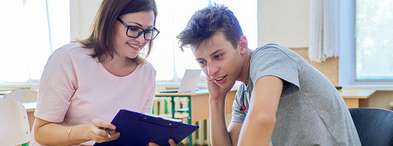 student and teacher looking at a clipboard together