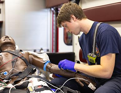 EMT student working on a mannequin in an ambulance