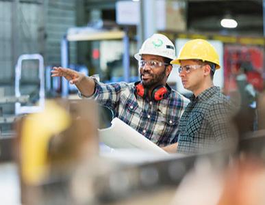 two coworkers in an industrial setting discussing plans